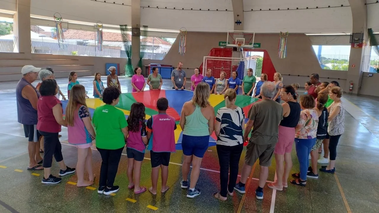 Grupo intergeracional em roda durante atividade coletiva com tecido colorido
